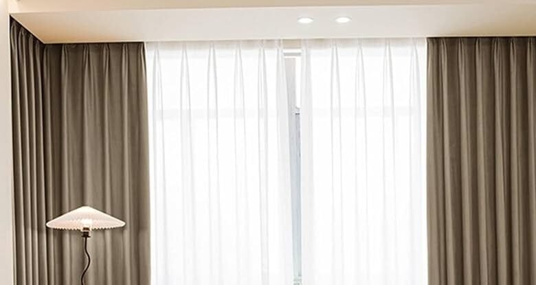 wohnzimmer mit sofa, beigen und weißen gardinen